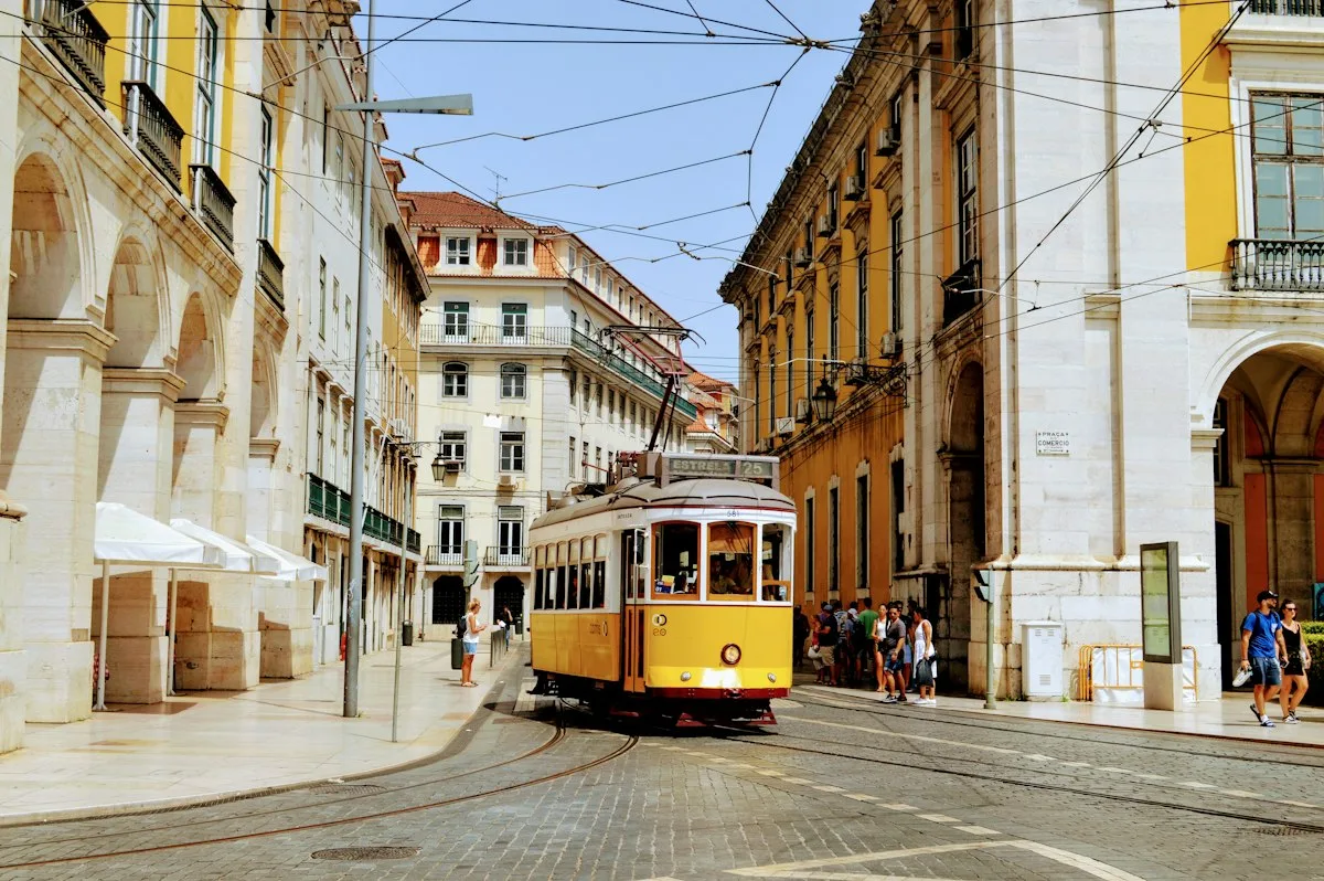 A yellow tram in a Lisbon street lined with historic buildings