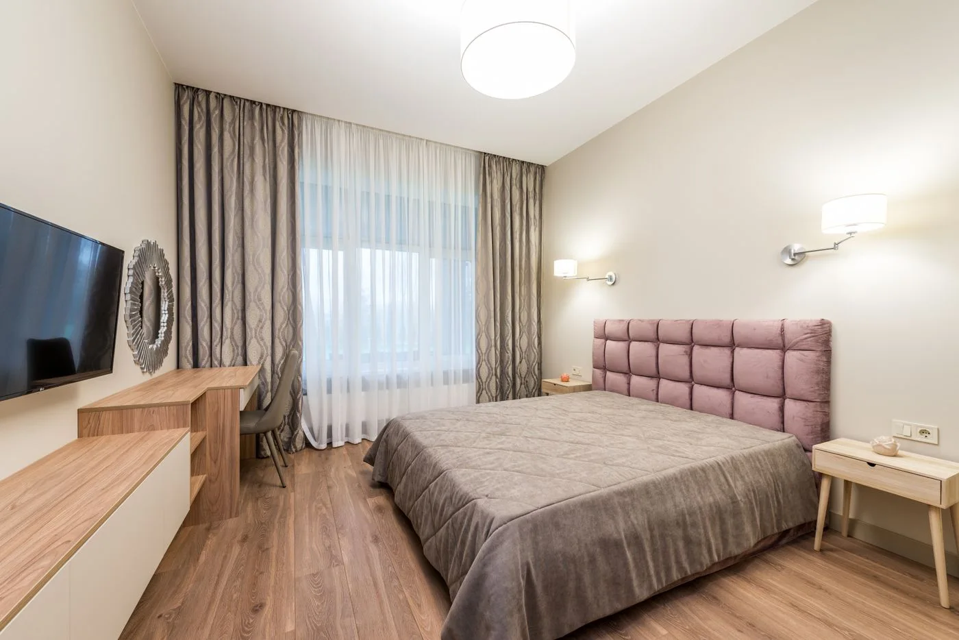 A bedroom with a television, curtains and a ceiling light
