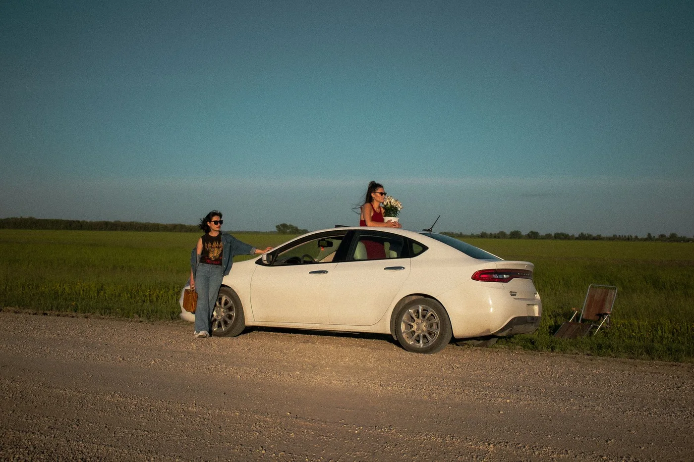 Two people beside and at a white car in open countryside