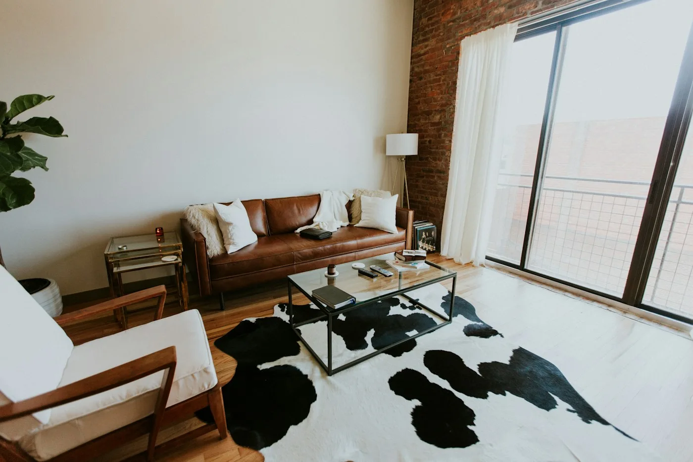Living room with a leather sofa, large windows, glass table and patterned rug