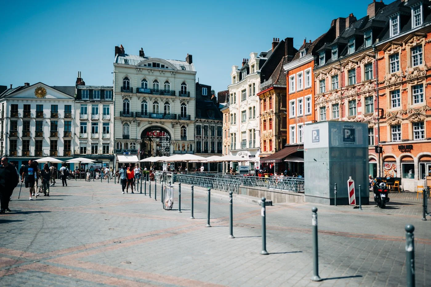 Pedestrians and colorful buildings at Grand Place in Lille.